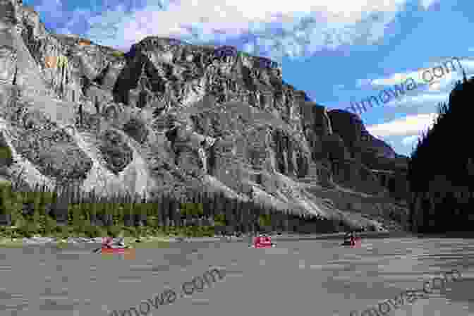 A Canoeist Paddles Down The Nahanni River, Surrounded By Towering Cliffs And Lush Greenery. Canoe On The Nahanni DH Koester